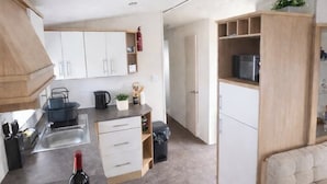 Una cucina moderna con zona pranzo, un divano e un piccolo tavolo con una bottiglia e un limone.