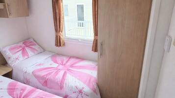 Een slaapkamer met twee bedden, een raam met gordijnen, een kledingkast en een radiator.