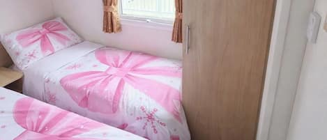 Un dormitorio con dos camas, una ventana con cortinas, un armario y un radiador.