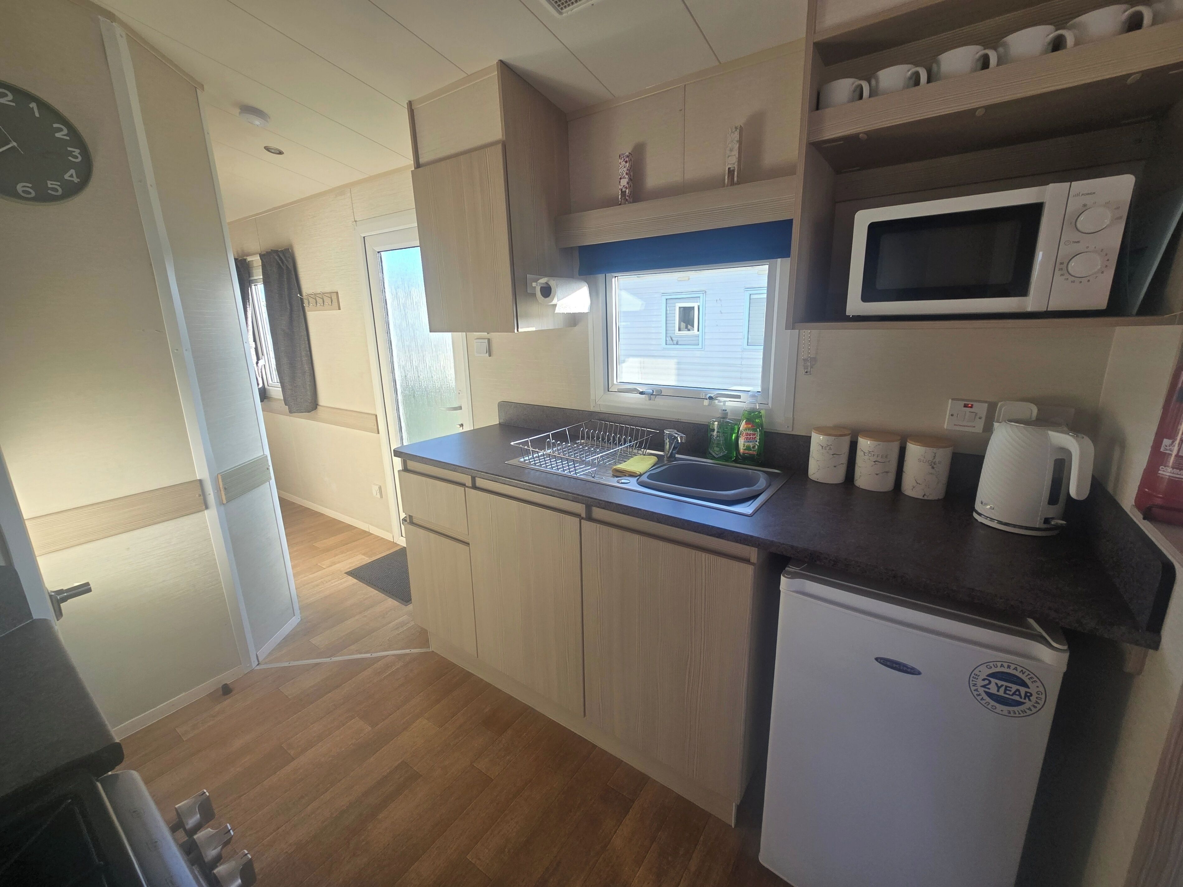 A compact kitchen with a microwave, kettle, and a small refrigerator.