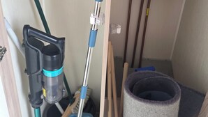A utility room with a water heater, a vacuum cleaner, a mop, and cleaning tools. - Caravan Paul Sleeps 6 With Free Parking (Rhyl)