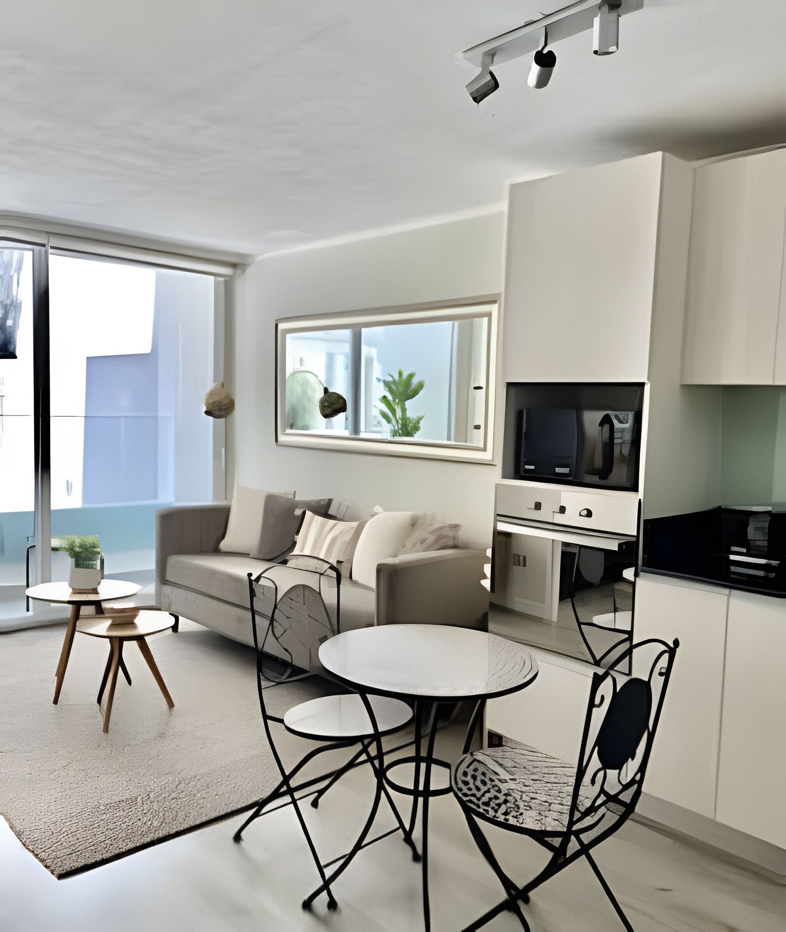 A modern living room with a sofa, a coffee table, and a dining table. There is a kitchen area with cabinets and a TV.