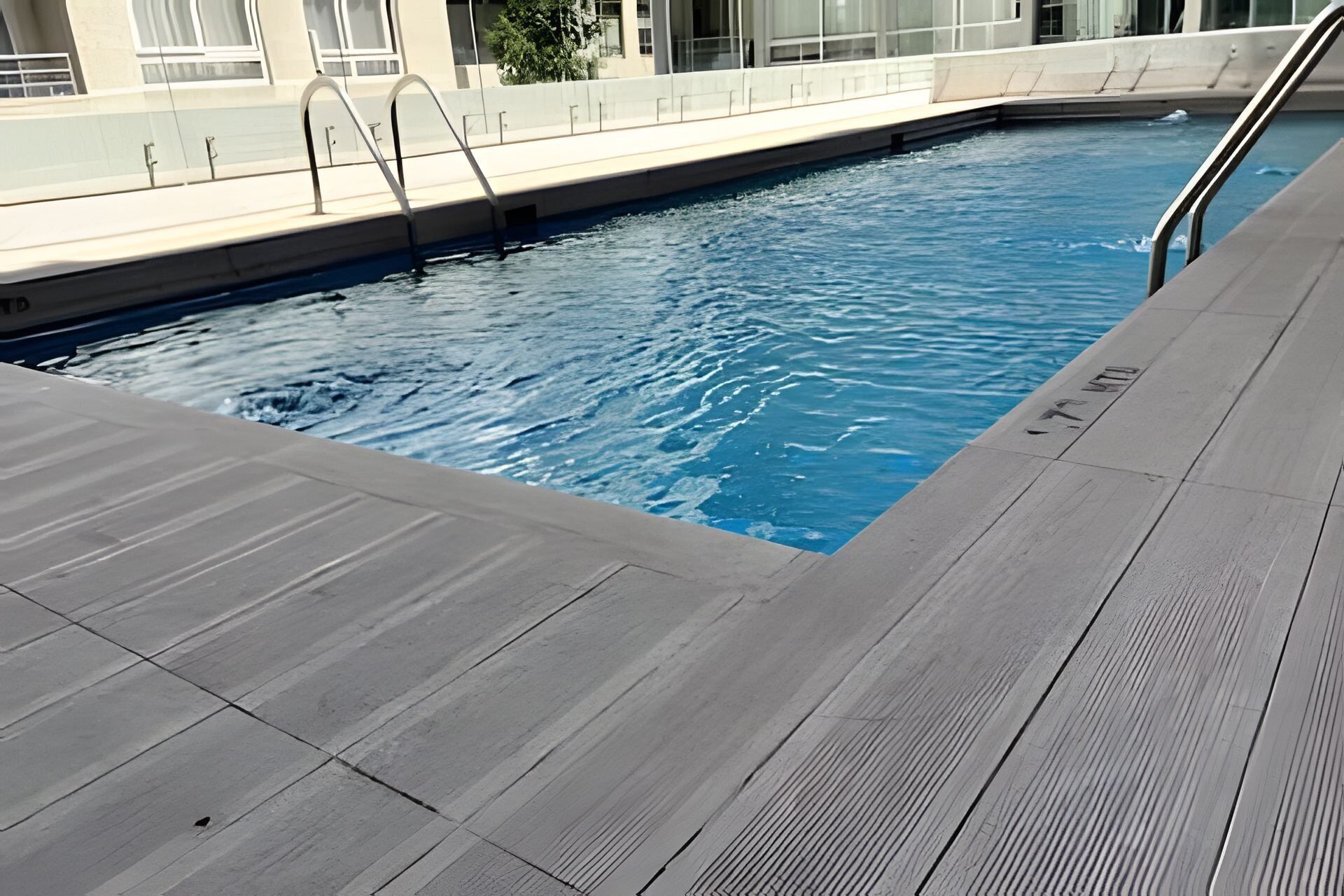 Ein Schwimmbecken mit Holzdeck und Metallhandläufen.
