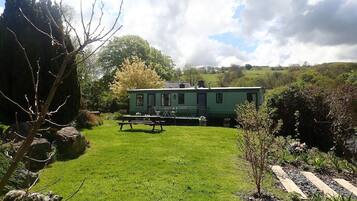 A green mobile home with a picnic table in a grassy yard.