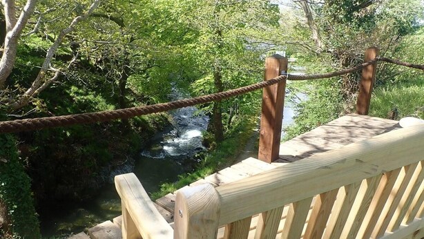 A wooden deck overlooking a river with a rope barrier. - Welsh Countryside Retreat - Felin Crewi Cottages (Machynlleth)