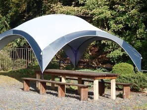 A picnic area with a wooden bench and a table under a large, white, semi-circular canopy. - Welsh Countryside Retreat - Felin Crewi Cottages (Machynlleth)