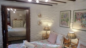 A bedroom with two beds, a wooden wardrobe, a mirror, and two lamps. - Welsh Countryside Retreat - Felin Crewi Cottages (Machynlleth)