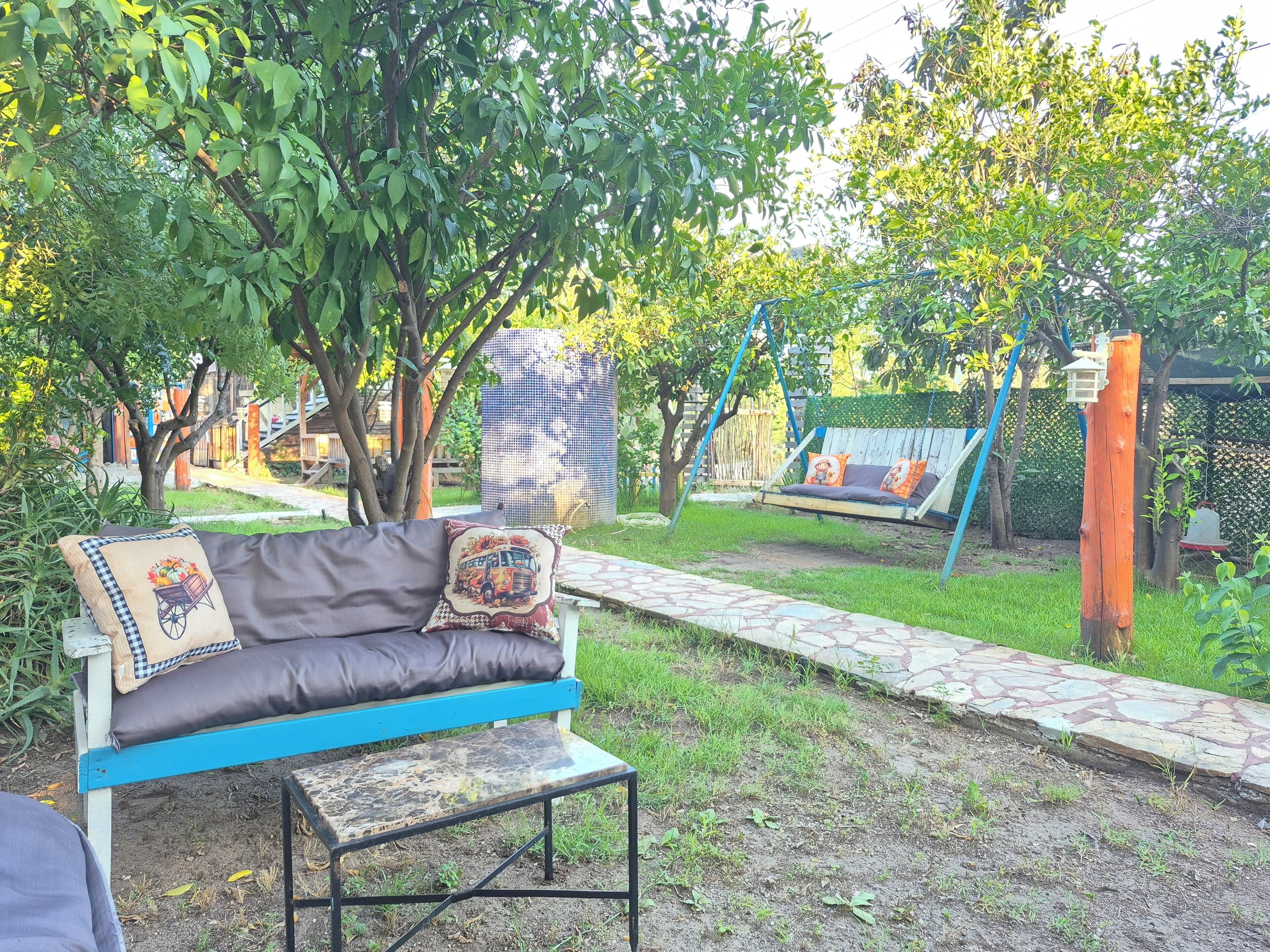 Un jardín con un banco azul, una mesa pequeña y un columpio.