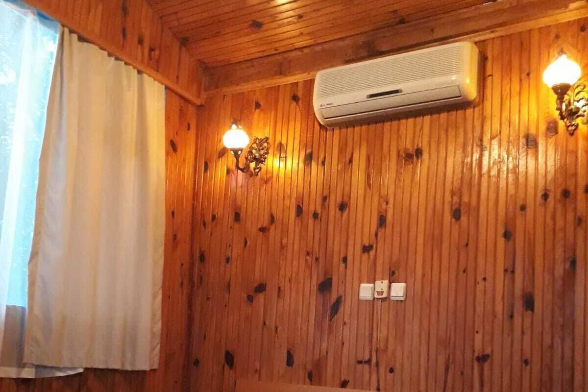 Puupaneloitu huone, jossa on sänky, kaksi seinälle asennettua valaisinta ja ilmastointilaite.