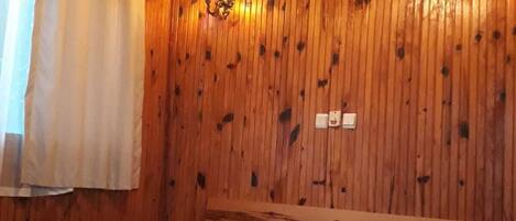 Een kamer met houten lambrisering, een bed, twee wandlampen en een airconditioning.
