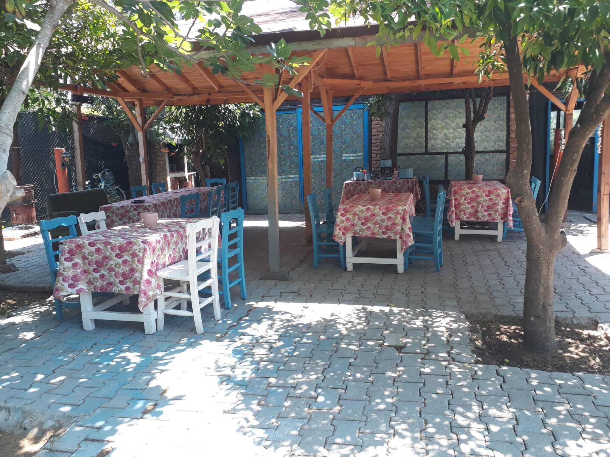 An outdoor patio with tables and chairs under a wooden pergola.