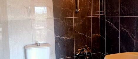 A bathroom with a toilet, a shower, and a sink.