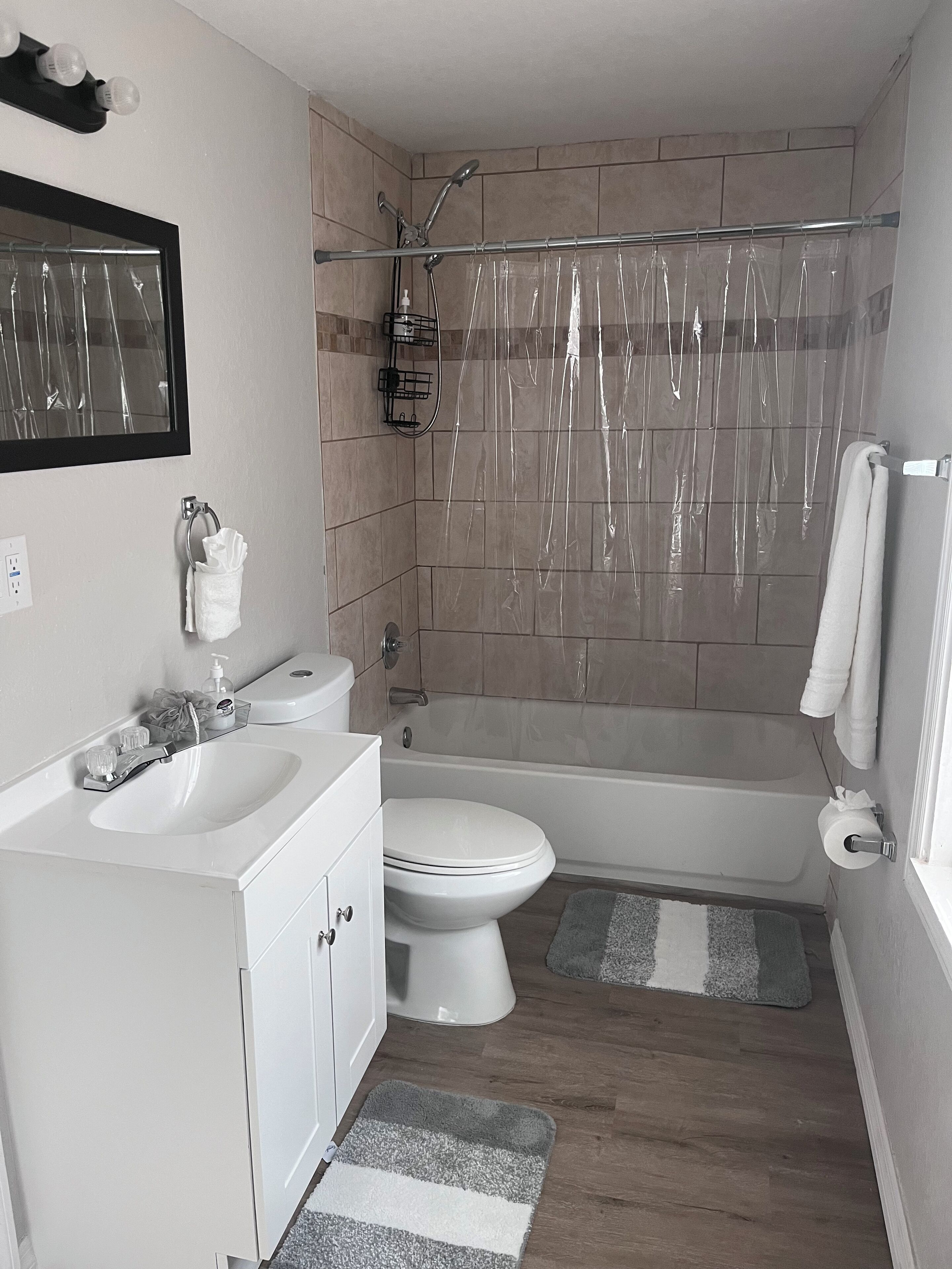 A bathroom with a white sink, toilet, and bathtub. There is a shower curtain, a towel rack, and a mirror on the wall.
