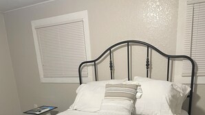 Ein Bett mit Metallgestell, weißer Bettwäsche und einer Streifen-Decke.