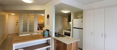 A compact kitchen with a wooden countertop, a built-in sink, and a white refrigerator.