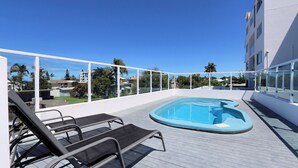 Uma área de piscina no terraço com espreguiçadeiras e vista para o bairro.
