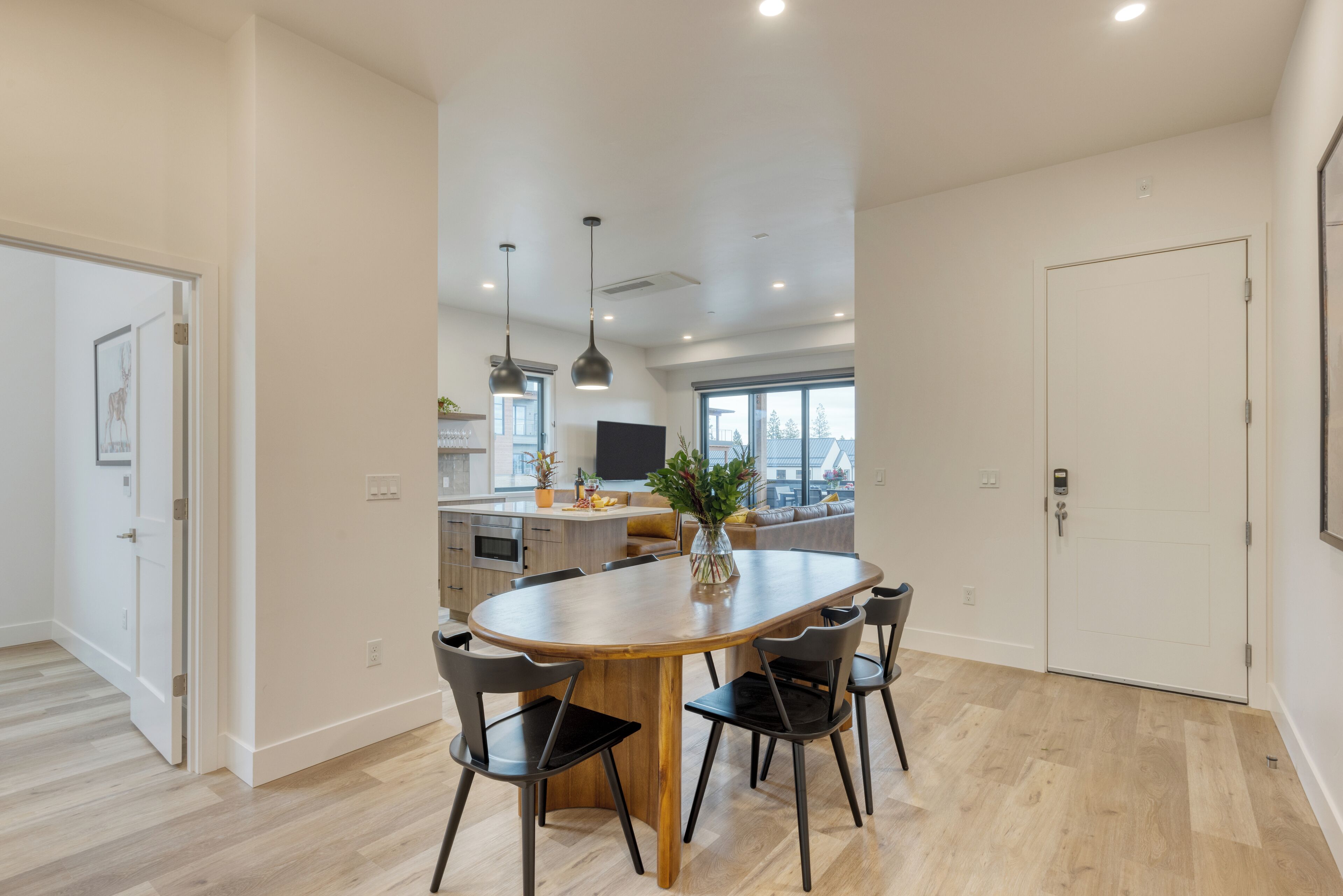 A modern kitchen with a central island, black chairs, and a large window.