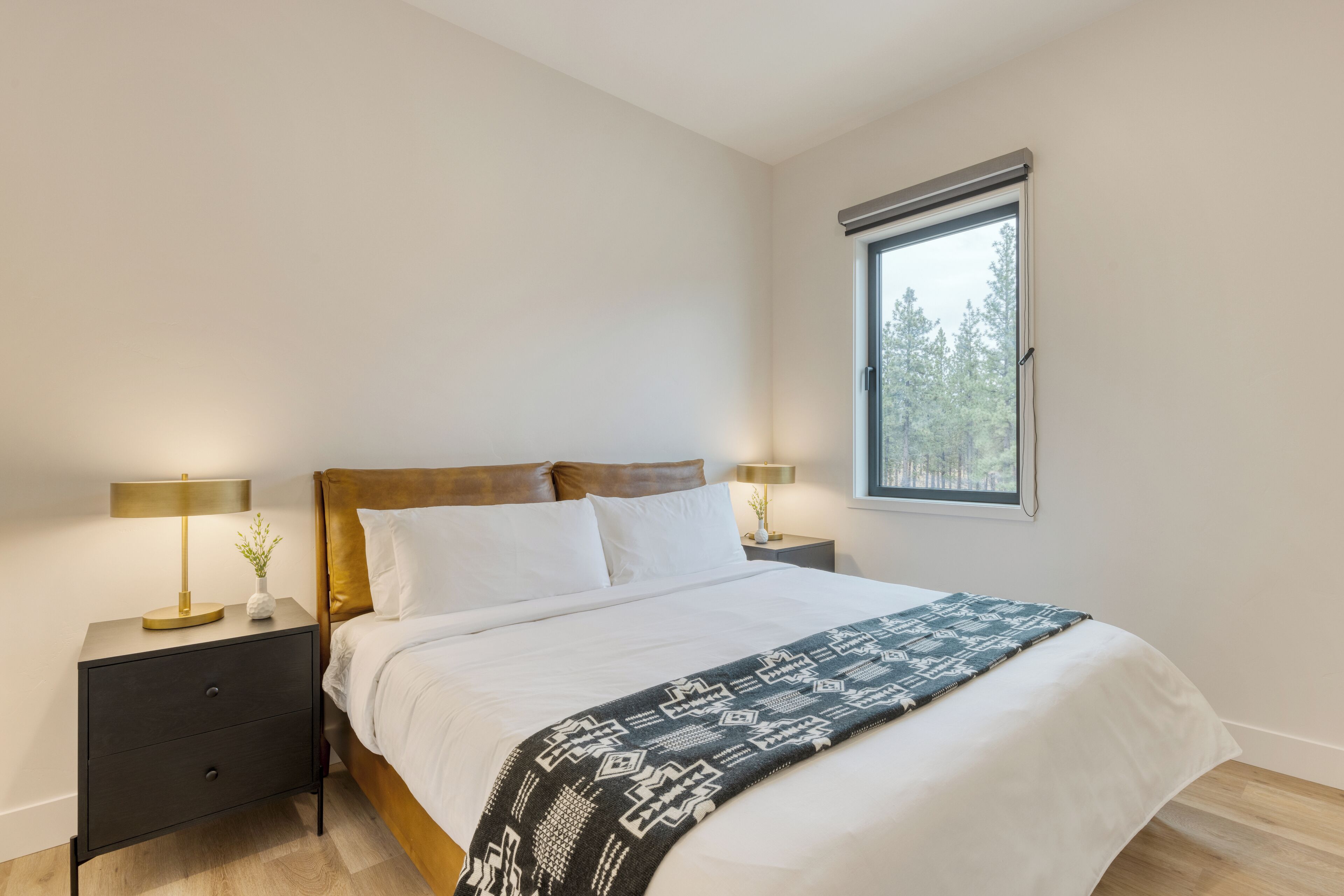 Une chambre à coucher avec un lit, deux tables de chevet, une fenêtre et une petite table.