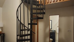 Una sala de estar con una escalera en espiral, un sofá, una mesa de centro y una alfombra.