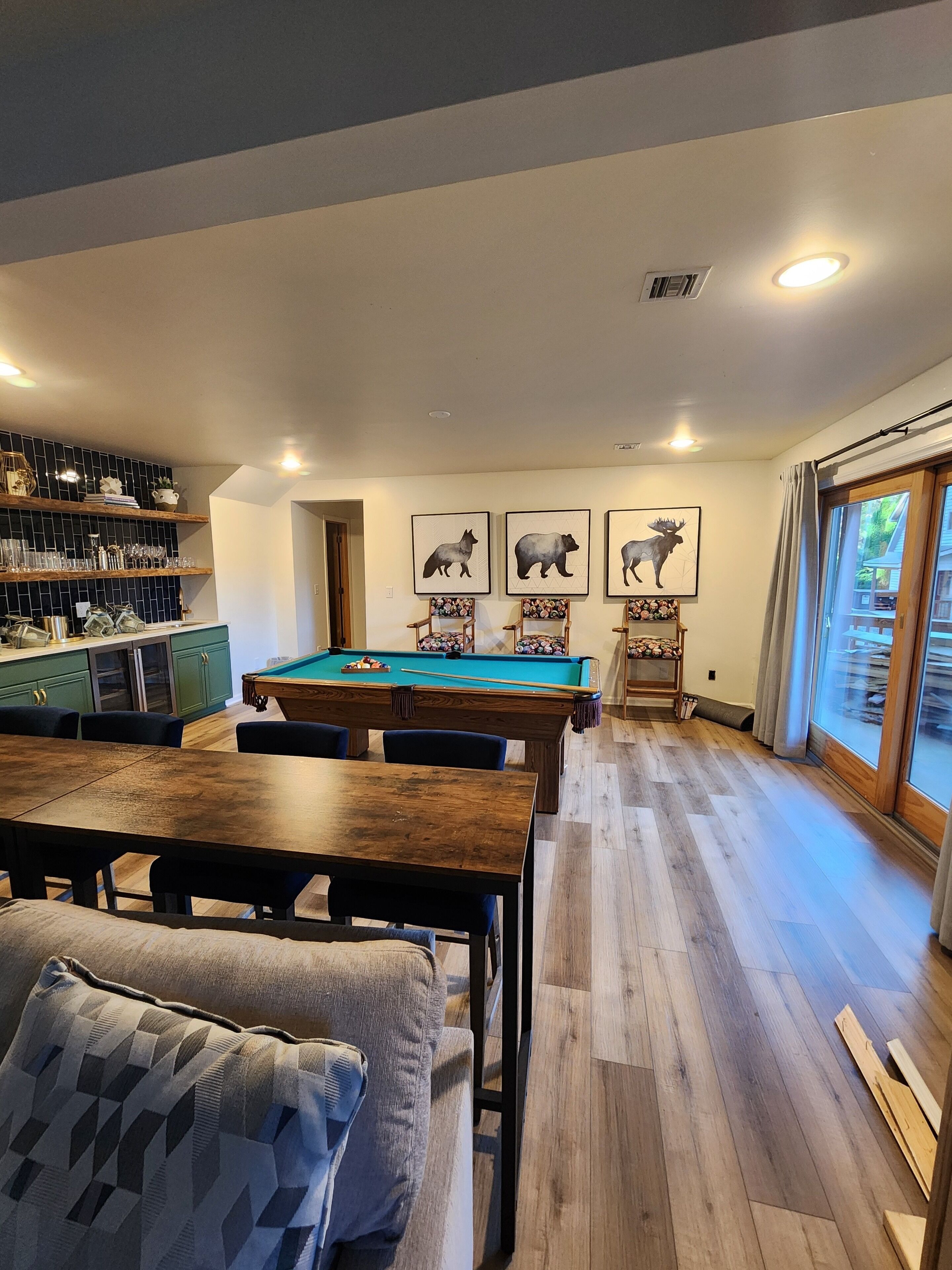 A cozy living room with a pool table, a dining area, and a kitchen with shelves.
