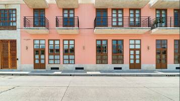 A row of pink buildings with balconies, windows, and a sign reading "CASA PEREIRA."