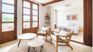 Una habitación amplia con una cama, dos sillones, una mesita y un ventanal grande.