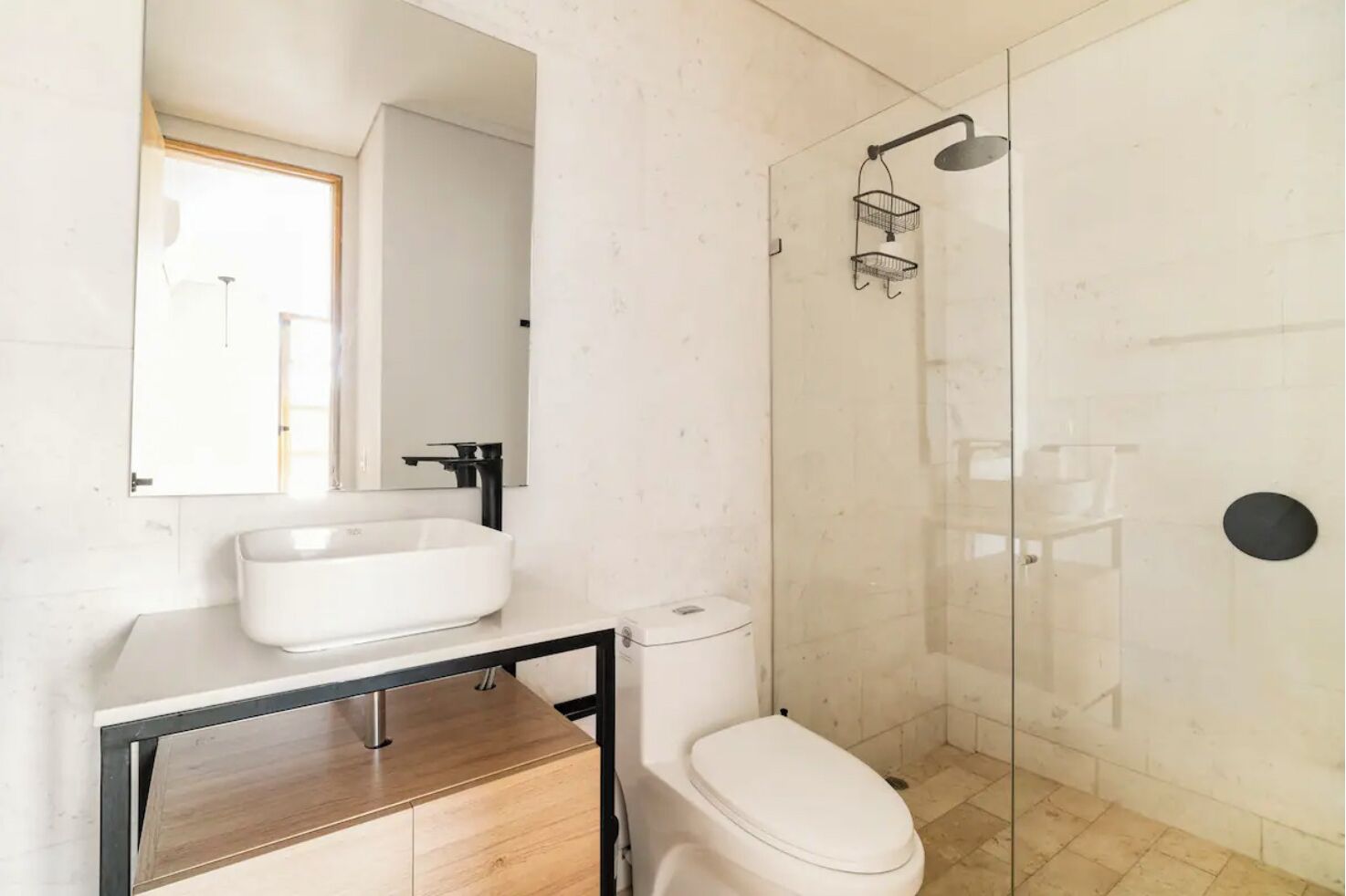Un baño moderno con lavamanos, inodoro y cabina de ducha de vidrio.