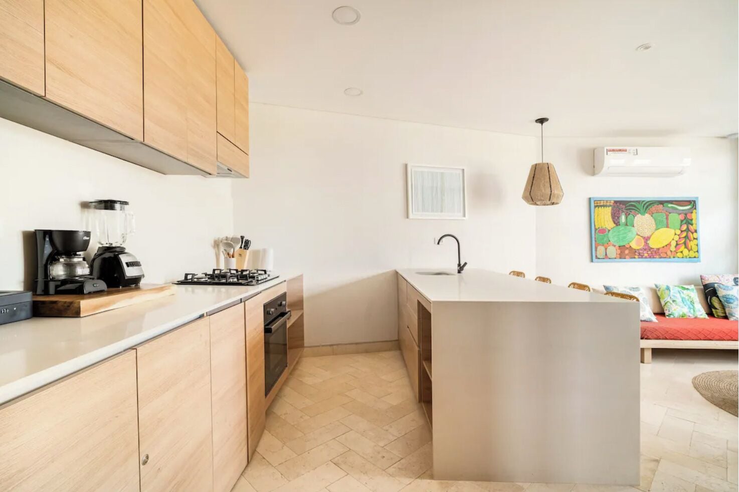 Una cocina moderna con armarios de madera, estufa integrada y una isla grande con lavamanos.