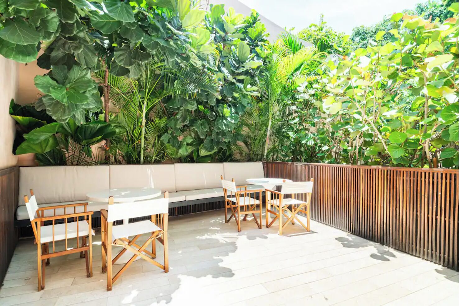 Un patio al aire libre con zona de estar, mesas y sillas.