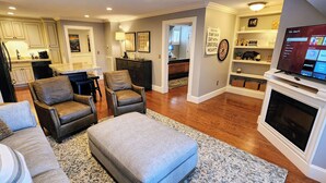 A modern living room with leather sofas, a grey ottoman, and a flat-screen TV. - The Loft at the Old Mill-Cozy 2-bedroom Loft in charming Pigeon Forge! (Pigeon Forge)