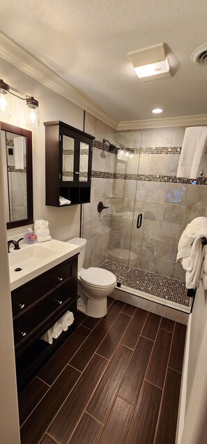 A modern bathroom with a shower, toilet, and vanity. - The Loft at the Old Mill-Cozy 2-bedroom Loft in charming Pigeon Forge! (Pigeon Forge)