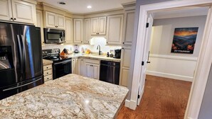 A modern kitchen with stainless steel appliances, a granite countertop, and light-colored cabinetry. - The Loft at the Old Mill-Cozy 2-bedroom Loft in charming Pigeon Forge! (Pigeon Forge)