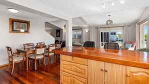 Un grand espace à manger avec une table et des chaises en bois, un comptoir de cuisine et une vue sur l’extérieur.