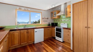 Une cuisine moderne avec des meubles en bois, un lave-vaisselle, une cuisinière et une fenêtre donnant sur l’extérieur.