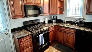 A kitchen with wooden cabinets, a stove, a microwave, and a sink. - Charming 3-bedroom house by Capitol Hill DC (Washington)