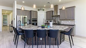 A modern kitchen with a central island, bar stools, and pendant lighting. - Havasu Peruvian - Resort Style Home, Swim Up Bar, Spa, FirePit (Lake Havasu City)