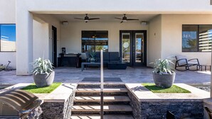 A modern outdoor patio with a stone staircase leading to a covered area, two ceiling fans, and potted plants. - Havasu Peruvian - Resort Style Home, Swim Up Bar, Spa, FirePit (Lake Havasu City)