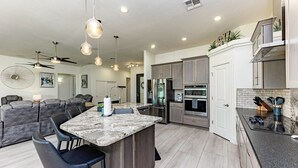 A modern kitchen with a central island, stainless steel appliances, and pendant lighting. - Havasu Peruvian - Resort Style Home, Swim Up Bar, Spa, FirePit (Lake Havasu City)