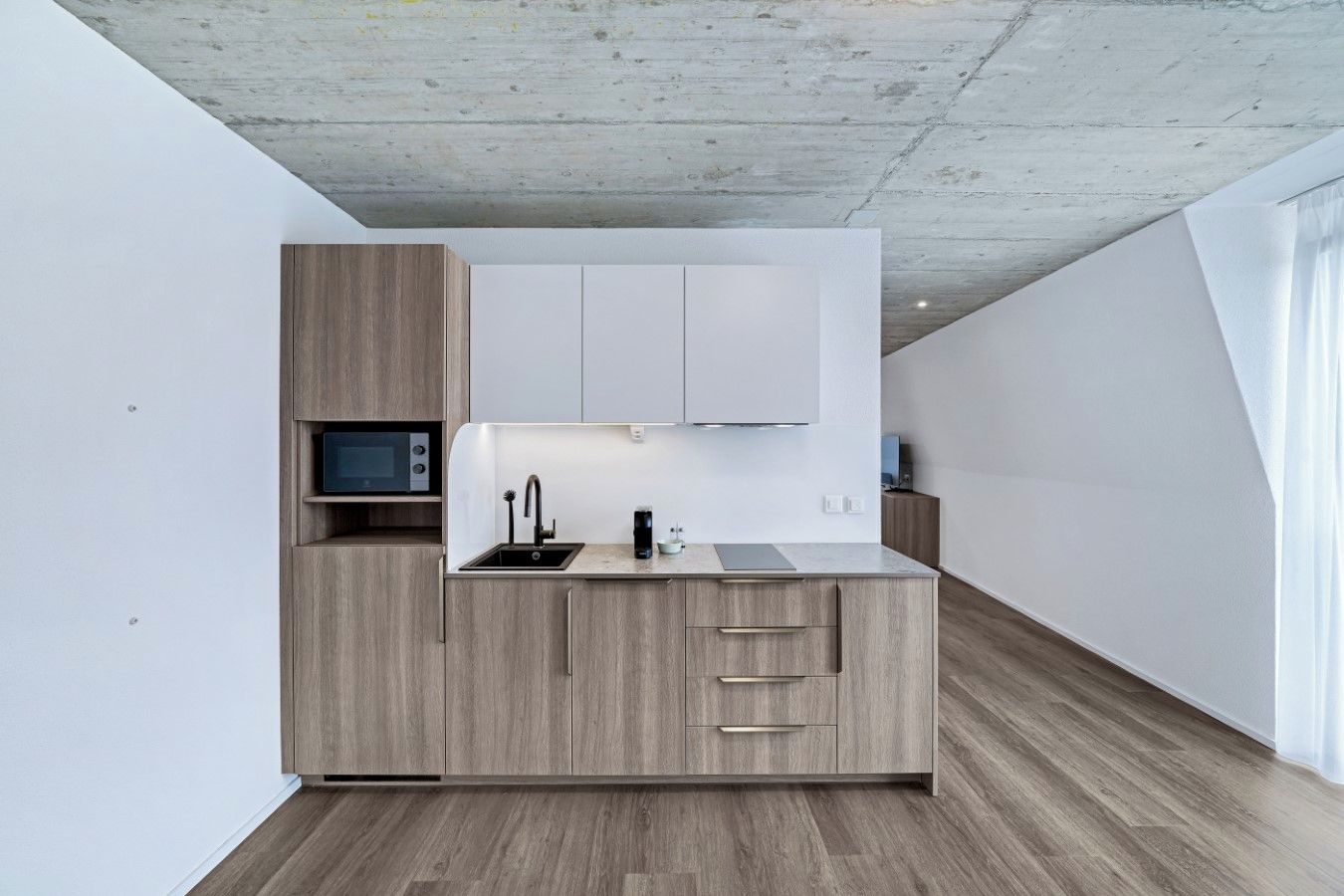 Eine moderne Küche mit Einbau-Mikrowelle, Spüle und Holzschränken.