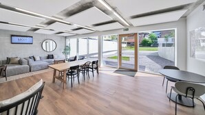 A modern office space with a large wooden table, several chairs, a sofa, and a television screen displaying 'MOOI'. - Mooi Apartments Biel (Biel)