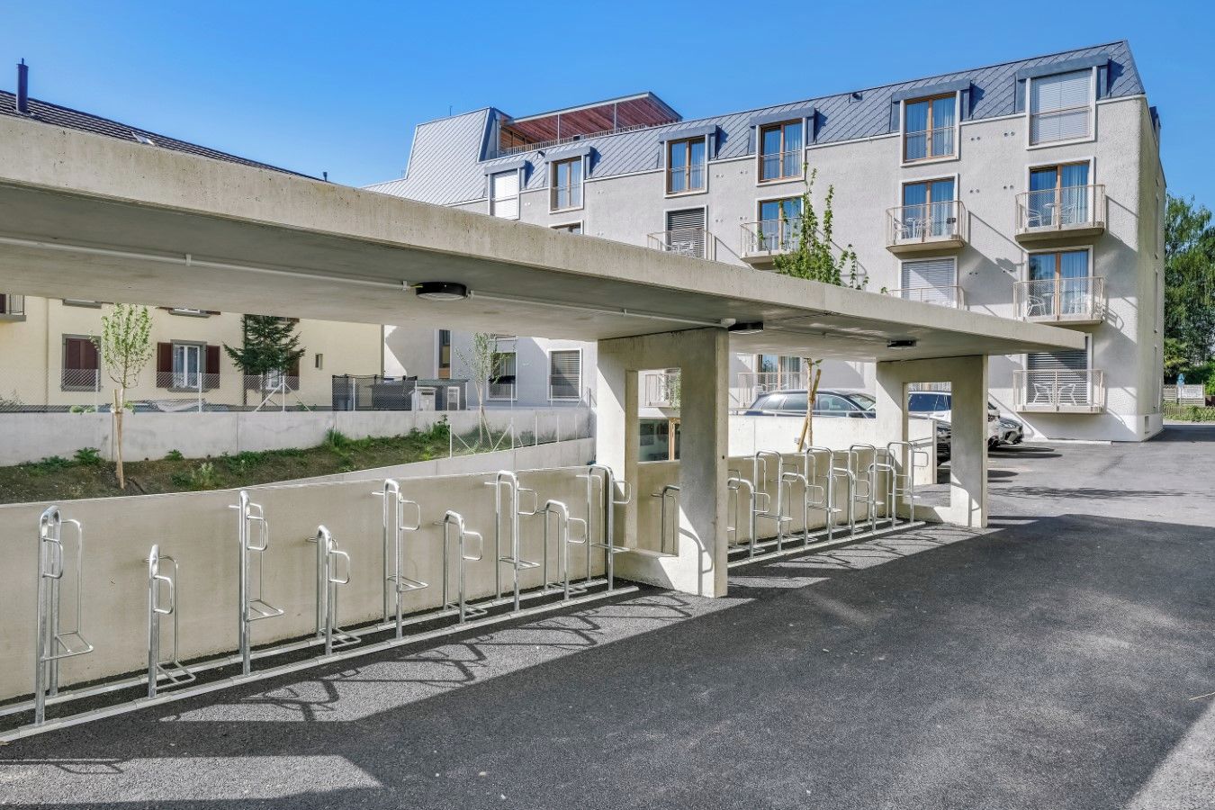 Ein Parkplatz mit überdachtem Gang, Metallgeländern und einer Reihe geparkter Autos.