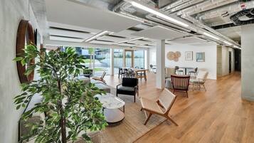 Un bureau spacieux, doté de mobilier moderne, de grandes fenêtres et de conduits apparents.