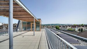 Une gare moderne dotée d’une salle d’attente couverte, de murs en verre et de panneaux solaires sur le toit.