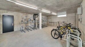 A bike parking area with multiple bike racks and a concrete floor. - Mooi Apartments Biel (Biel)