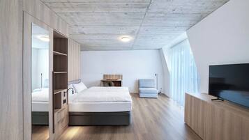 Une chambre moderne comprenant un lit, une armoire intégrée, une table de chevet, une lampe et un téléviseur.