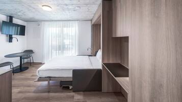 Une chambre à coucher moderne, avec un lit, un bureau et un téléviseur.