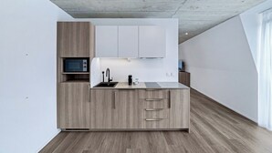 Une cuisine moderne dotée d’un four à micro-ondes encastré, d’un évier et de meubles de rangement en bois.