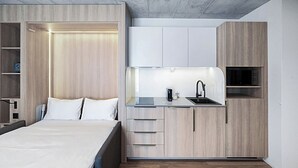 Une chambre à coucher de taille réduite, comprenant un lit, une table de chevet et une armoire intégrée.