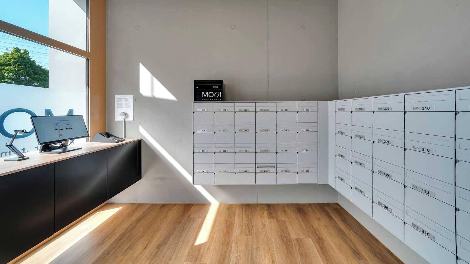 Ein modernes Büro mit Schreibtisch, Computer und einer Wand voller nummerierter Aufbewahrungsboxen.