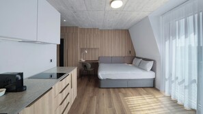 Une chambre moderne équipée d’un lit, d’un bureau et d’une kitchenette.